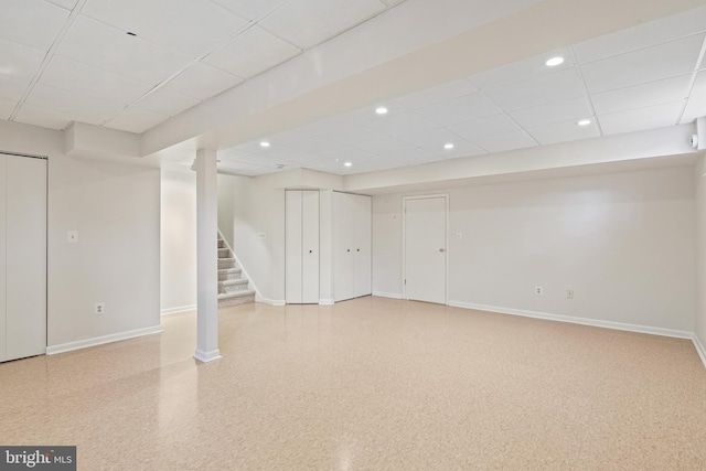 finished basement with a drop ceiling, stairway, and baseboards