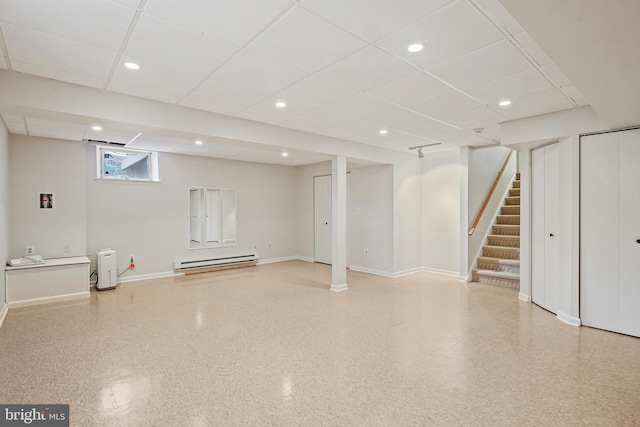 below grade area with stairway, baseboards, a drop ceiling, and a baseboard radiator