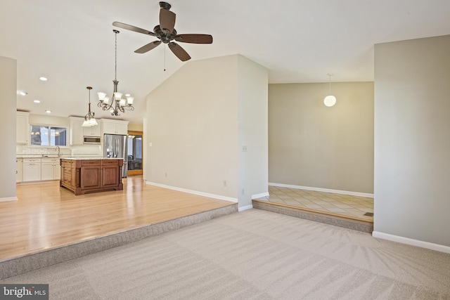 interior space featuring baseboards, vaulted ceiling, light carpet, light wood-style floors, and a sink