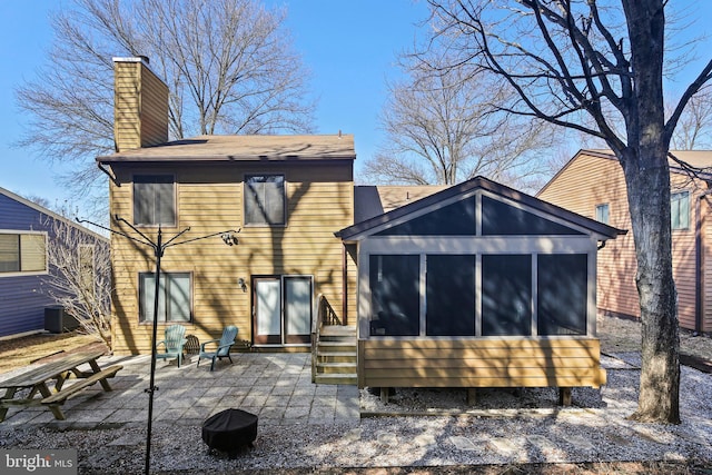 rear view of house with a patio area, central AC unit, a chimney, and a sunroom