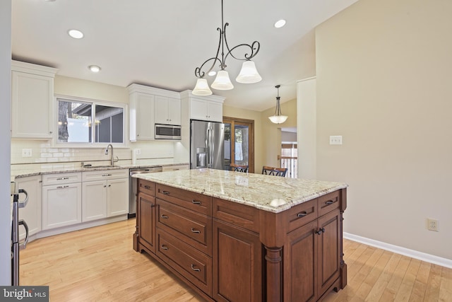 kitchen with a sink, stainless steel appliances, backsplash, and white cabinets