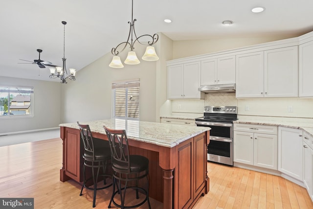 kitchen featuring double oven range, a kitchen island, lofted ceiling, under cabinet range hood, and backsplash