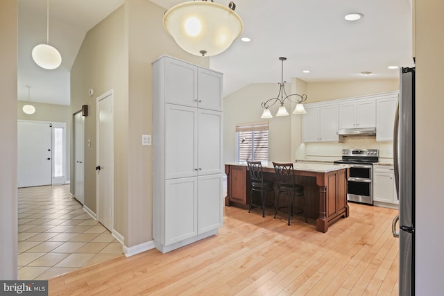 kitchen featuring a kitchen bar, under cabinet range hood, backsplash, appliances with stainless steel finishes, and light wood finished floors