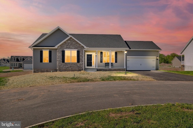 view of front of property featuring a garage, stone siding, and driveway