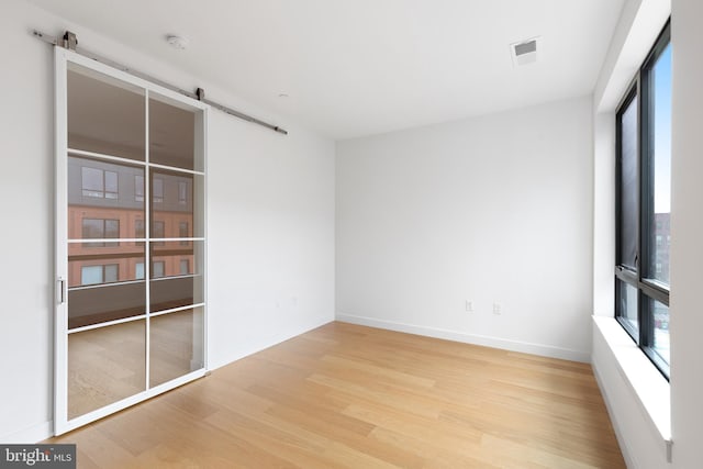 7175 12th St NW Unit 601, Washington, DC 20011 - spare room with baseboards, visible vents, a barn door, and wood finished floors