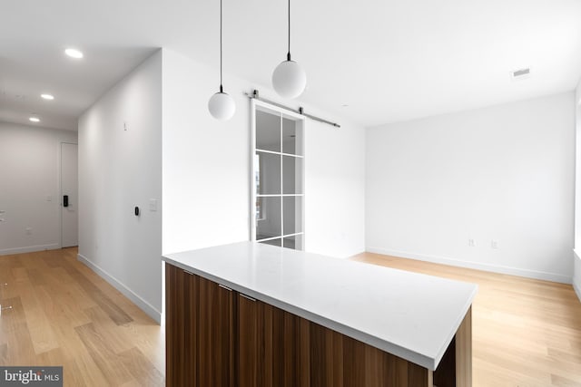 7175 12th St NW Unit 601, Washington, DC 20011 - kitchen with a barn door, recessed lighting, baseboards, light wood-type flooring, and visible vents