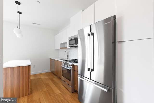 7175 12th St NW Unit 601, Washington, DC 20011 - kitchen with white cabinets, appliances with stainless steel finishes, a sink, light wood-style floors, and light countertops
