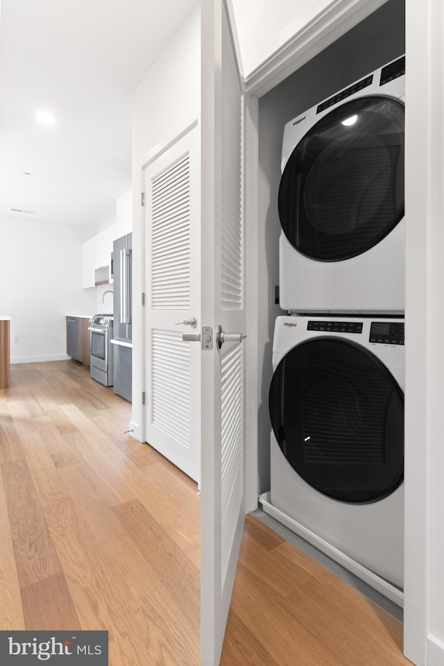 7175 12th St NW Unit 601, Washington, DC 20011 - laundry room featuring stacked washer and dryer, laundry area, baseboards, and light wood finished floors