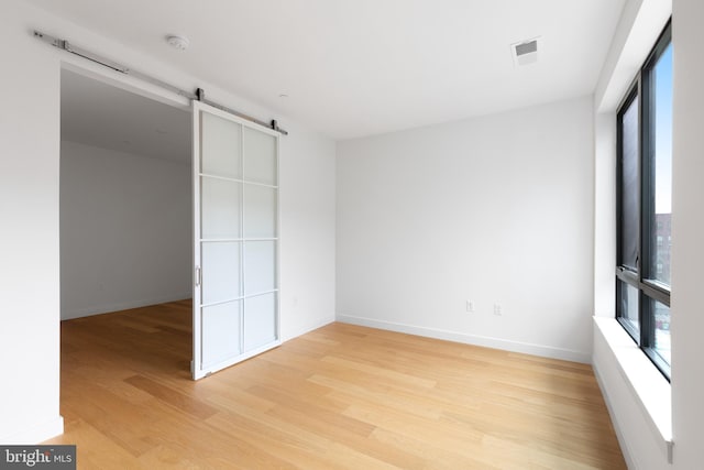 7175 12th St NW Unit 601, Washington, DC 20011 - unfurnished bedroom featuring light wood-style floors, baseboards, a barn door, and visible vents