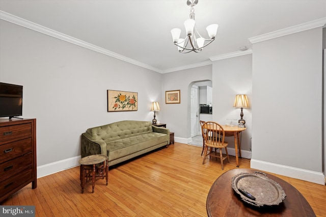 living area featuring arched walkways, light wood finished floors, an inviting chandelier, ornamental molding, and baseboards