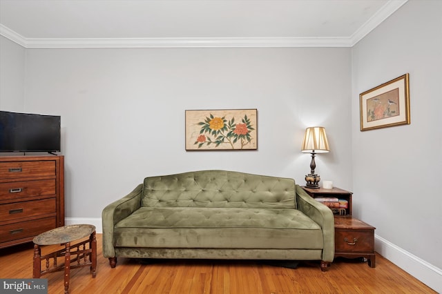 living area featuring ornamental molding, baseboards, and wood finished floors