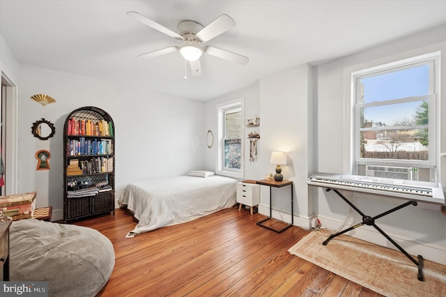 bedroom featuring ceiling fan, cooling unit, hardwood / wood-style flooring, and baseboards