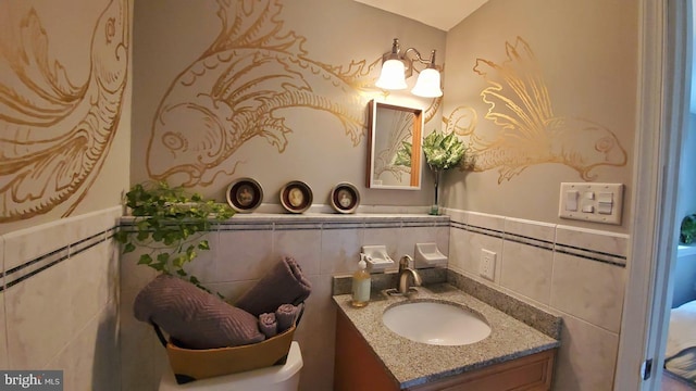 half bath featuring tile walls and vanity