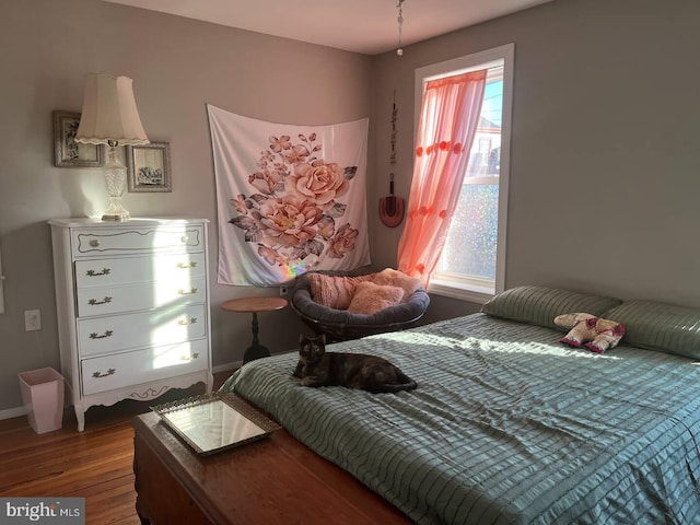 bedroom featuring multiple windows, wood finished floors, and baseboards