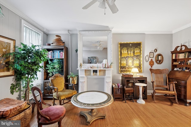 living area featuring ornamental molding, wood finished floors, and a ceiling fan