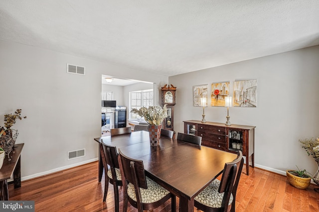 dining room featuring hardwood / wood-style flooring, visible vents, and baseboards