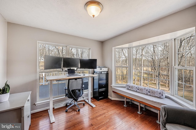 office space featuring a wealth of natural light, baseboards, a textured ceiling, and hardwood / wood-style floors