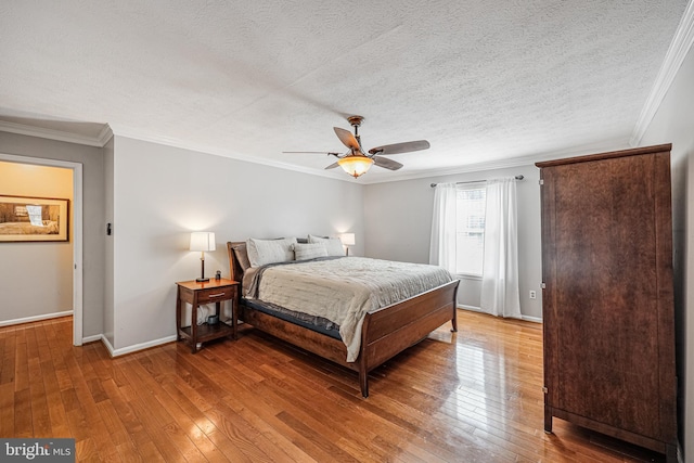 bedroom with a textured ceiling, ornamental molding, hardwood / wood-style flooring, and baseboards