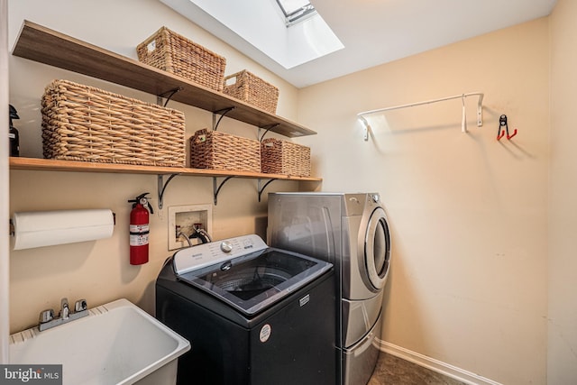 washroom with laundry area, a skylight, baseboards, washer and clothes dryer, and a sink