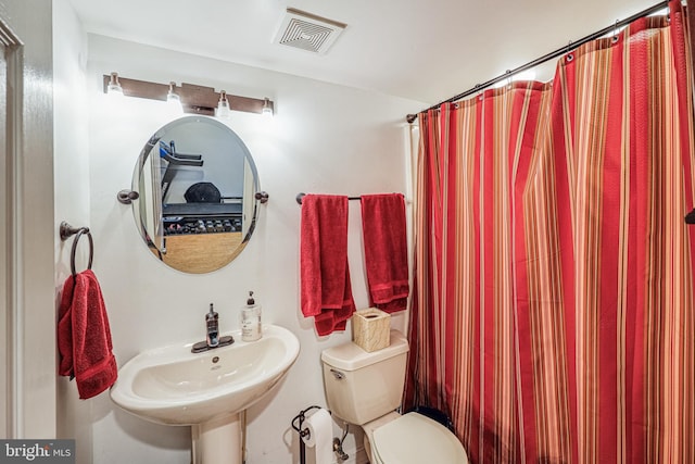 full bath with toilet, curtained shower, a sink, and visible vents