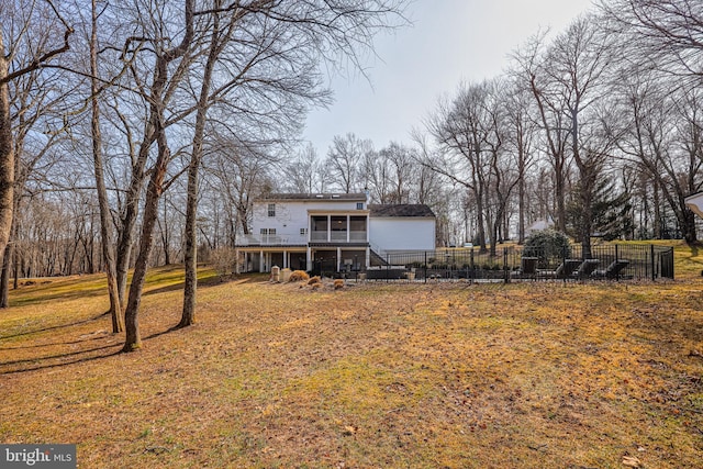 rear view of property featuring a sunroom, stairway, fence, and a lawn