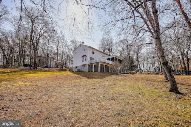 view of property exterior with a sunroom, a yard, and a chimney