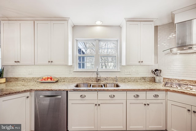 kitchen with white cabinets, appliances with stainless steel finishes, a sink, light stone countertops, and backsplash