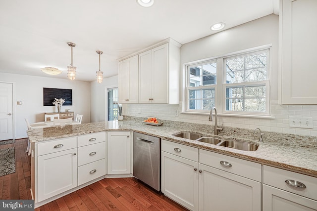 kitchen with a peninsula, a sink, white cabinets, dishwasher, and dark wood finished floors