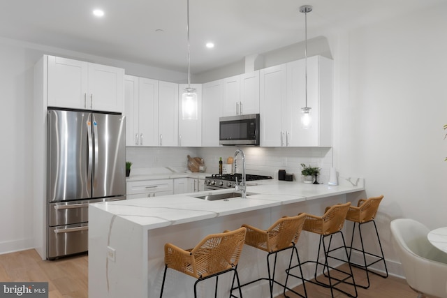 kitchen with a peninsula, tasteful backsplash, a breakfast bar area, and stainless steel appliances