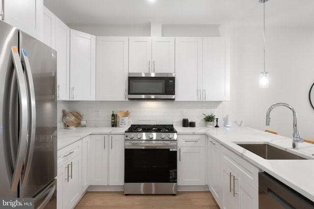 kitchen featuring backsplash, white cabinetry, stainless steel appliances, and a sink