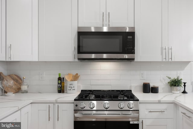 kitchen with light stone countertops, white cabinetry, appliances with stainless steel finishes, and decorative backsplash