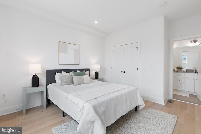 bedroom with recessed lighting, a closet, light wood-type flooring, and baseboards