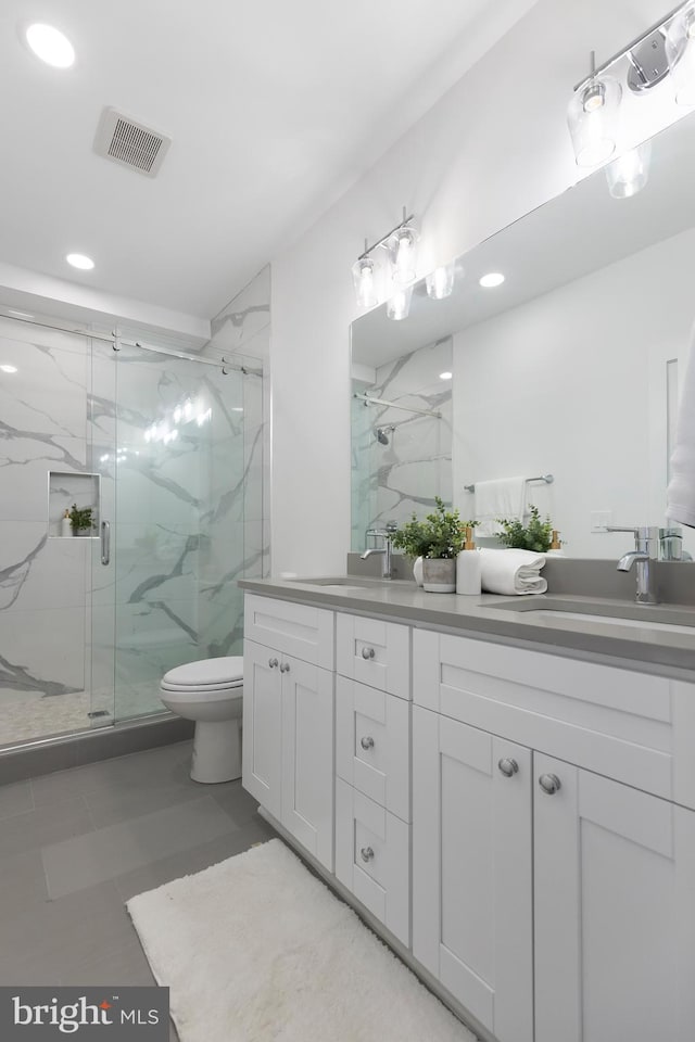 bathroom featuring visible vents, a sink, a marble finish shower, and double vanity