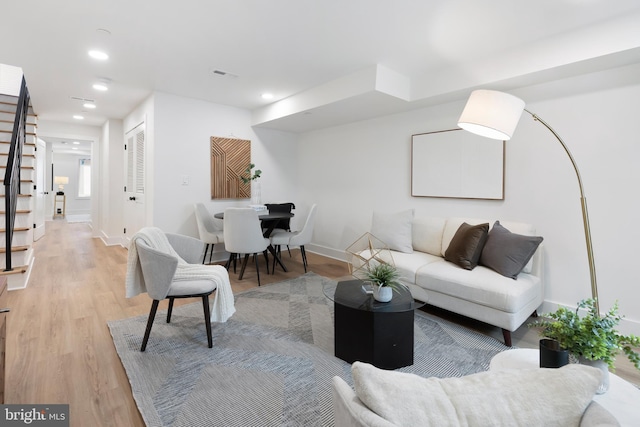 living room with recessed lighting, visible vents, stairway, light wood-style floors, and baseboards