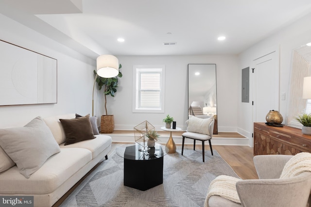 living area with recessed lighting, electric panel, visible vents, and wood finished floors