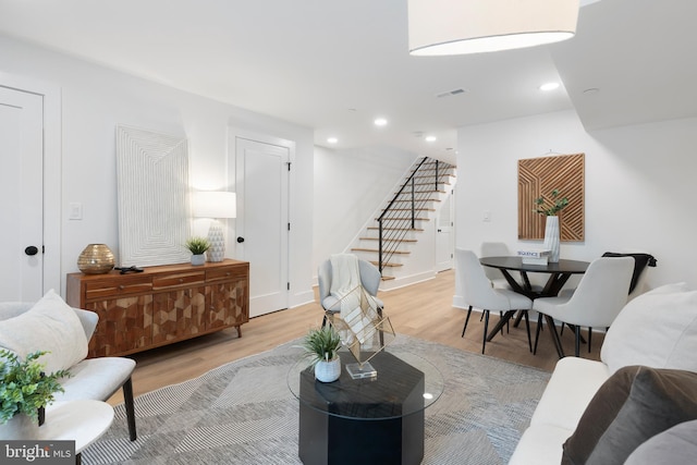 living area featuring recessed lighting, visible vents, light wood-style flooring, baseboards, and stairs