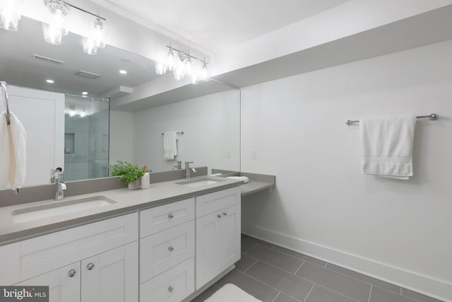 bathroom with double vanity, a stall shower, a sink, and baseboards