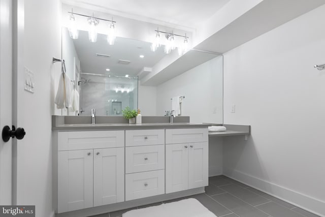 bathroom with double vanity, a stall shower, a sink, and baseboards