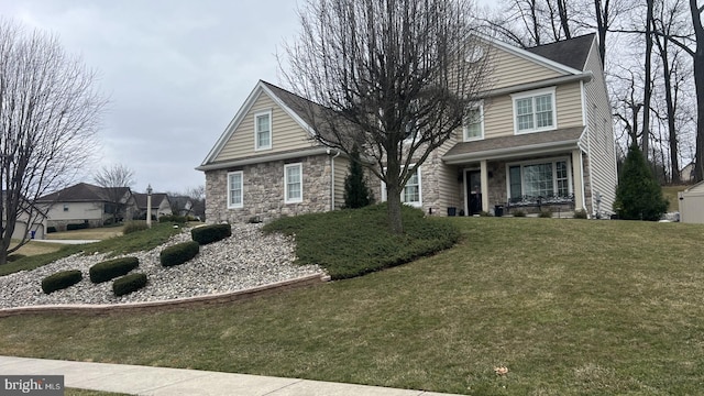 traditional-style house featuring a front yard and stone siding