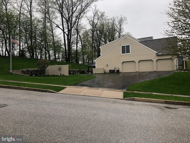 view of side of home featuring driveway and a lawn