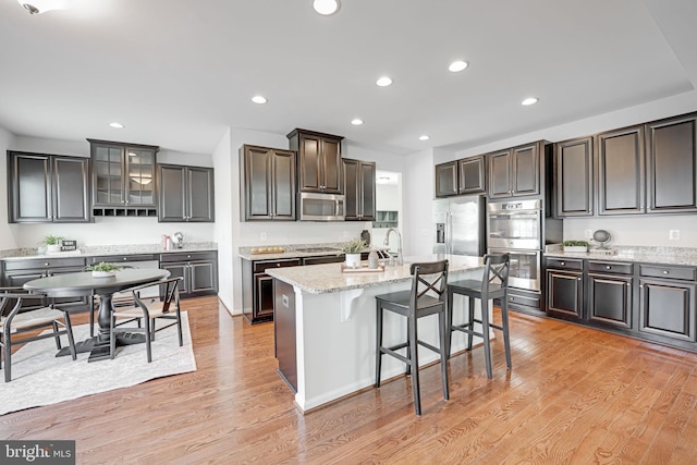 kitchen featuring light wood finished floors, recessed lighting, stainless steel appliances, and a kitchen island with sink