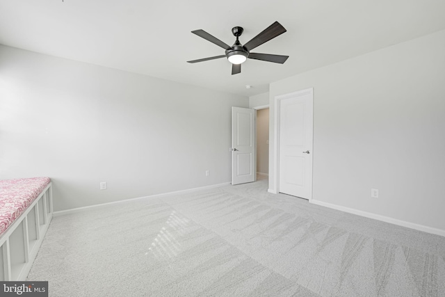 unfurnished bedroom featuring baseboards, light colored carpet, and ceiling fan