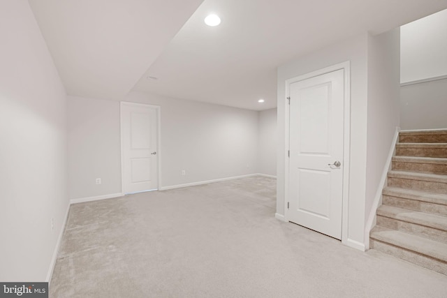 finished below grade area with light carpet, stairway, recessed lighting, and baseboards