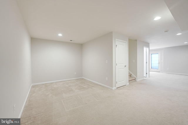 below grade area featuring stairs, recessed lighting, baseboards, and light carpet