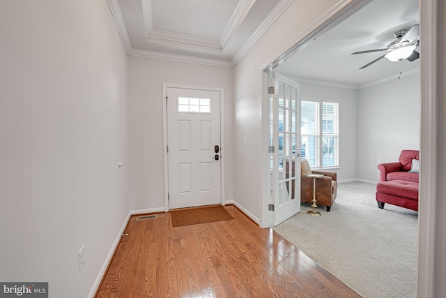 foyer entrance with visible vents, ornamental molding, a ceiling fan, wood finished floors, and baseboards