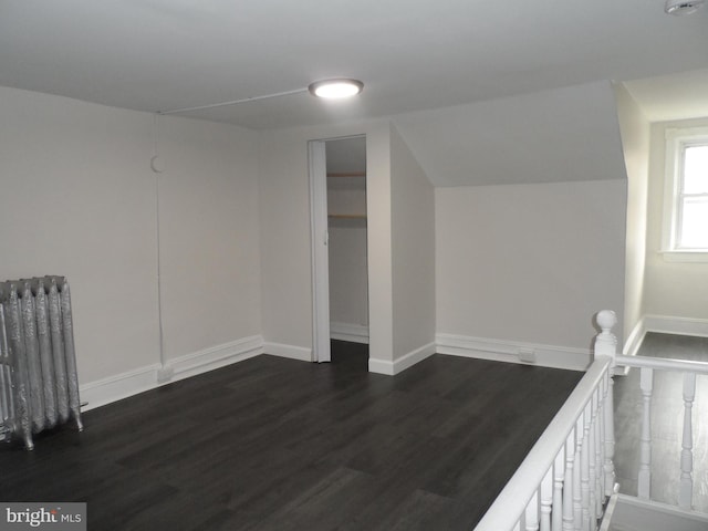 additional living space featuring vaulted ceiling, radiator heating unit, dark wood finished floors, and baseboards