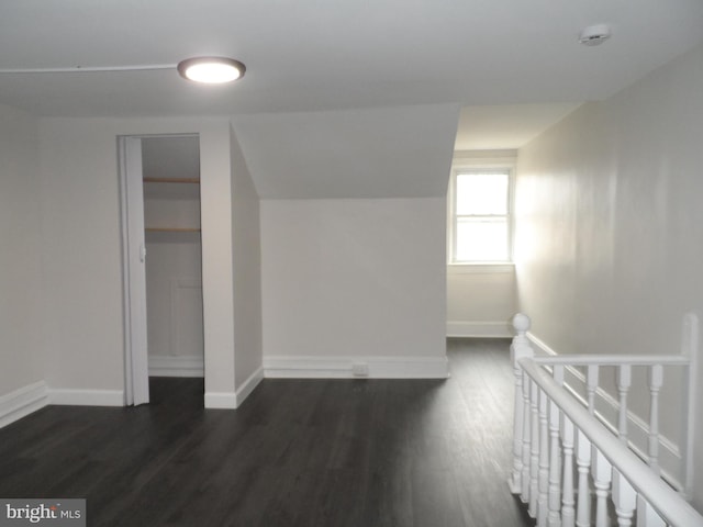 bonus room with baseboards, vaulted ceiling, and dark wood-type flooring