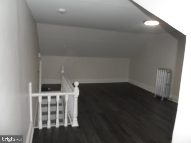 bonus room with lofted ceiling, radiator heating unit, dark wood finished floors, and baseboards