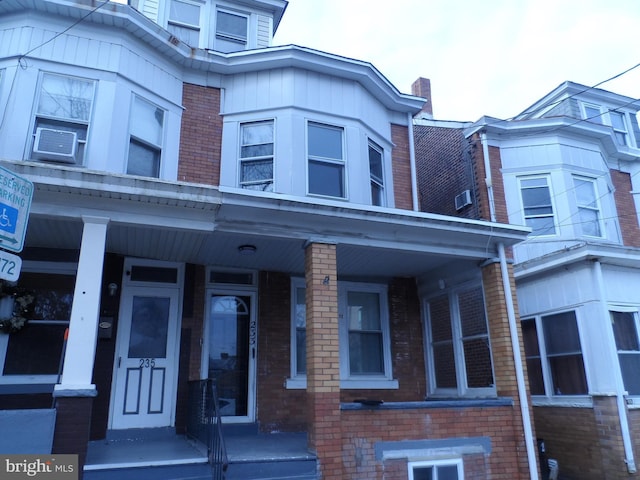 view of property with brick siding and a porch