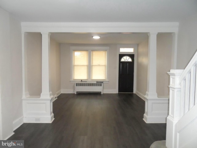 foyer featuring stairway, dark wood finished floors, decorative columns, and radiator